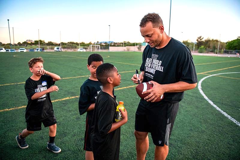 Alec Ingold signs footballs for kids at the Alec Ingold greets local Las Vegas foster youth at 2022 Alec Ingold Youth Football Summit