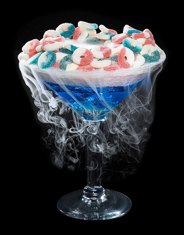 Dive In, a giant candy martini made with Smirnoff Pink Lemonade and Island Punch DeKuyper, rimmed with sugar and topped with blue raspberry and watermelon gummy rings. 