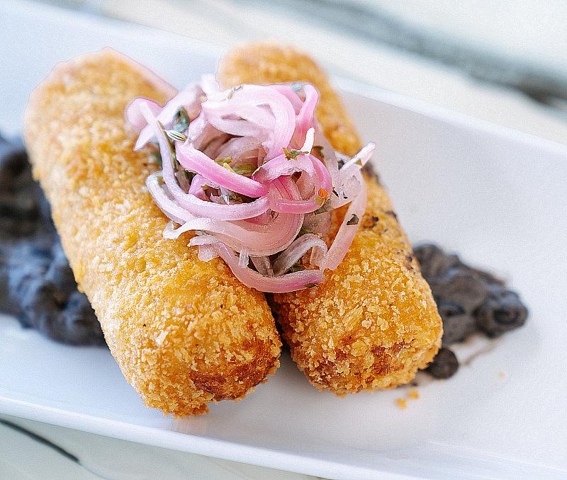 The STRAT Bolinho de Bacalhau, Alaskan cod fritters with spicy black bean sauce and pickled onions, at Top of the World, credit Cole Curtis 