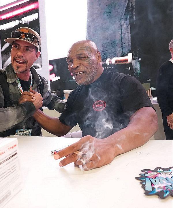 Mike Tyson posing with fan at CHAMPS 2024 Trade Show at the Las Vegas Convention Center.  