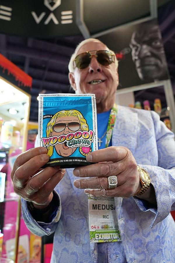 Ric Flair holding Wooooo! Chews at CHAMPS 2024 Trade Show at the Las Vegas Convention Center.